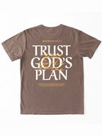 Faded brown T-shirt laid flat with a large back design reading “JEREMIAH 29:11” and “TRUST GOD’S PLAN,” with the verse below.