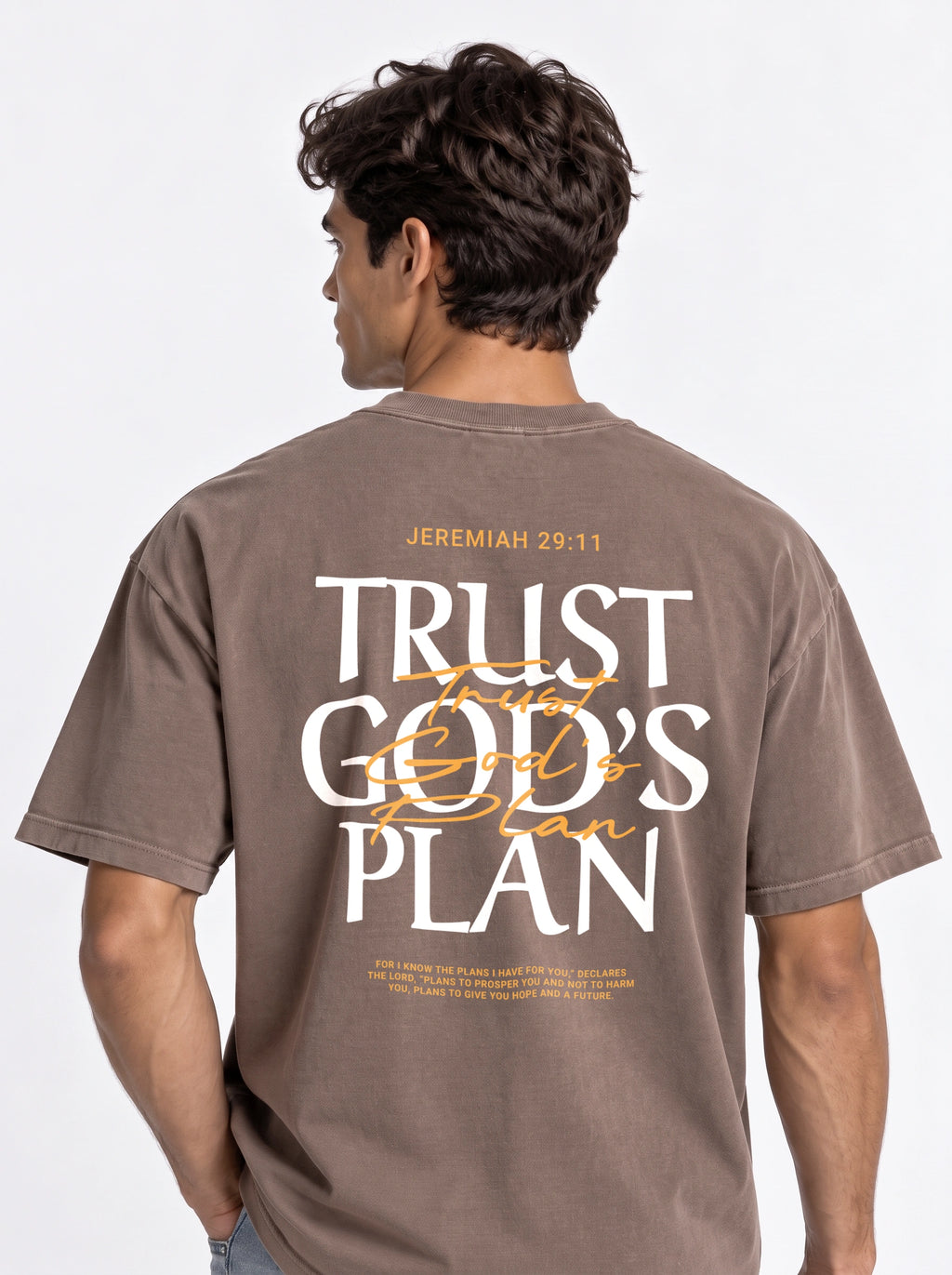 Person shown from behind wearing a faded brown T-shirt with a large “JEREMIAH 29:11” and “TRUST GOD’S PLAN” design with the verse below.