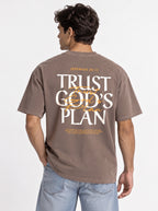 Person shown from behind wearing a faded brown T-shirt with a large “JEREMIAH 29:11” and “TRUST GOD’S PLAN” design with the verse below.