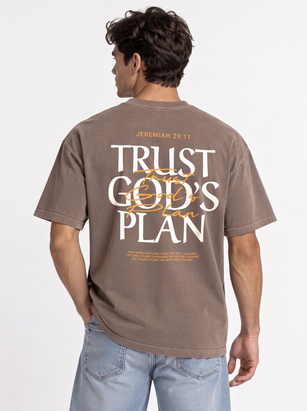 Person shown from behind wearing a faded brown T-shirt with a large “JEREMIAH 29:11” and “TRUST GOD’S PLAN” design with the verse below.