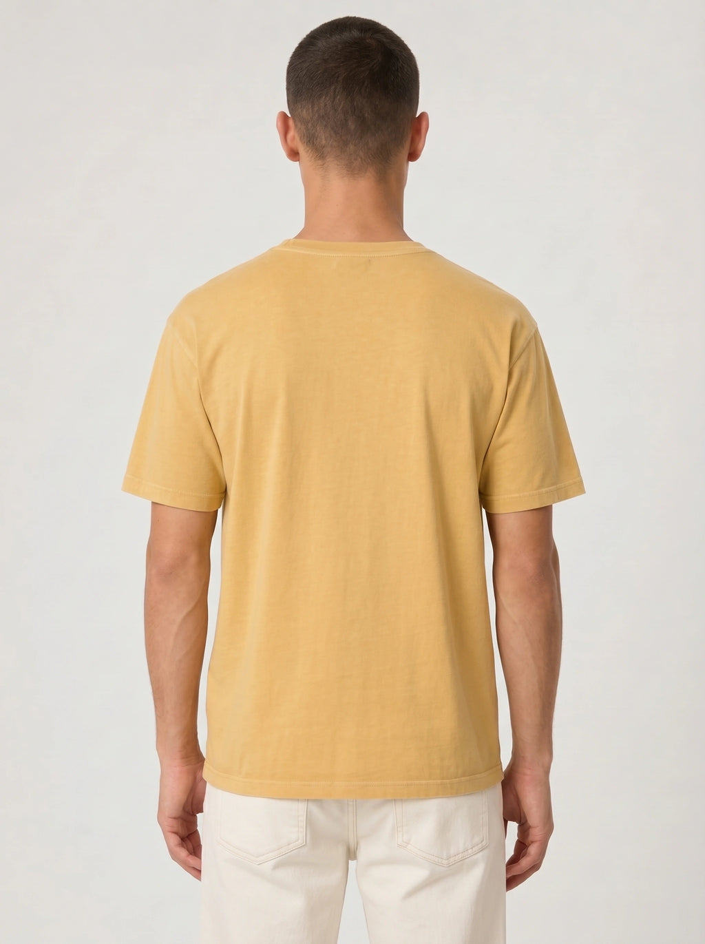 Back view of a person wearing a plain mustard yellow T-shirt.