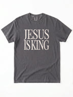Charcoal gray T-shirt laid flat with distressed cream text reading “Jesus Is King.”