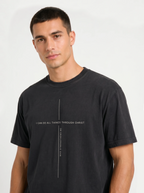 Person wearing a black T-shirt with a minimalist cross formed by the text “I can do all things through Christ” and “who strengthens me.”