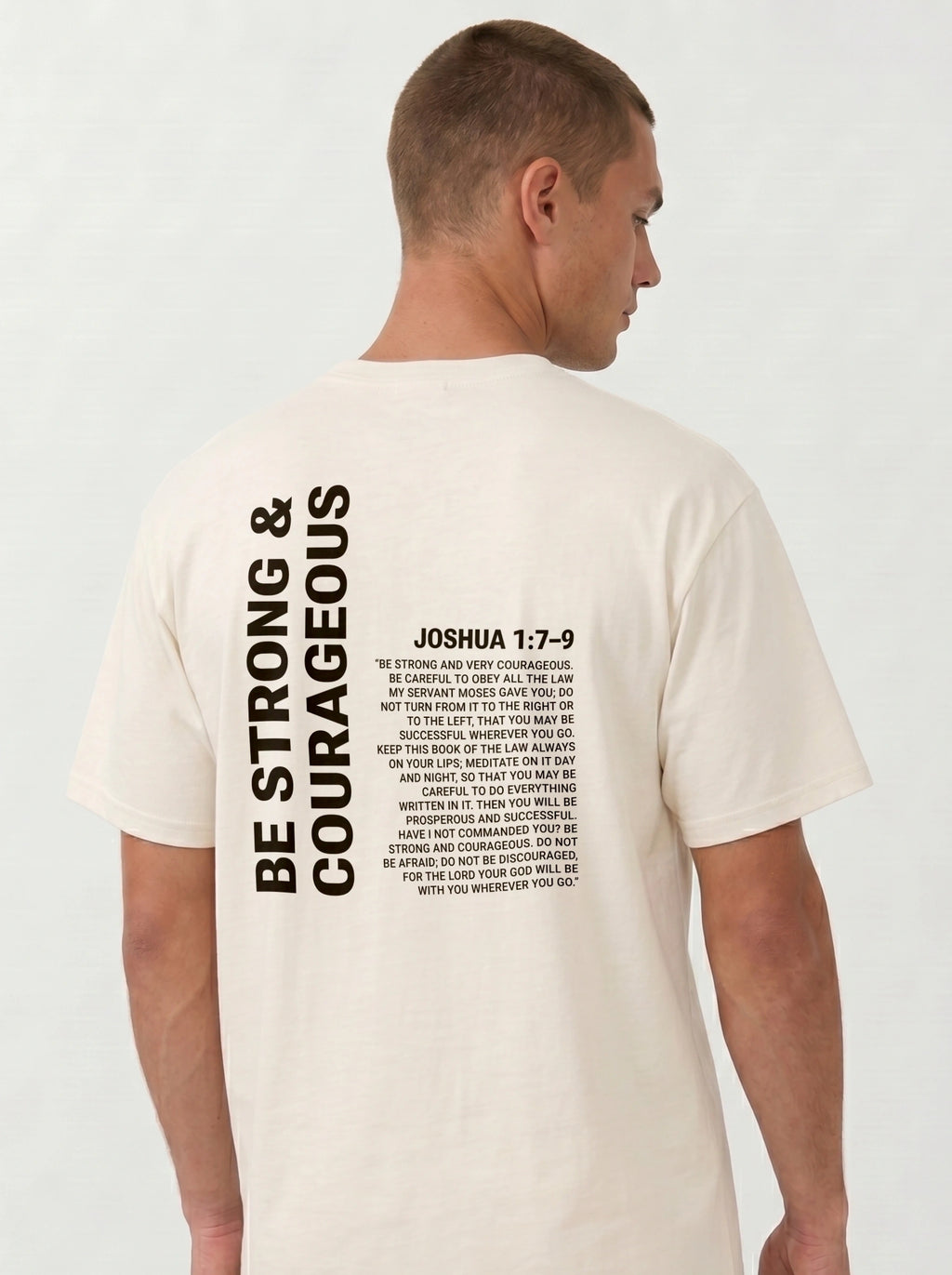 Person wearing a cream T-shirt with “Be strong & courageous” and Joshua 1:7–9 printed across the back.