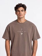 Person wearing a faded brown T-shirt with a cross, “PSALM 23” text, and dove graphic.