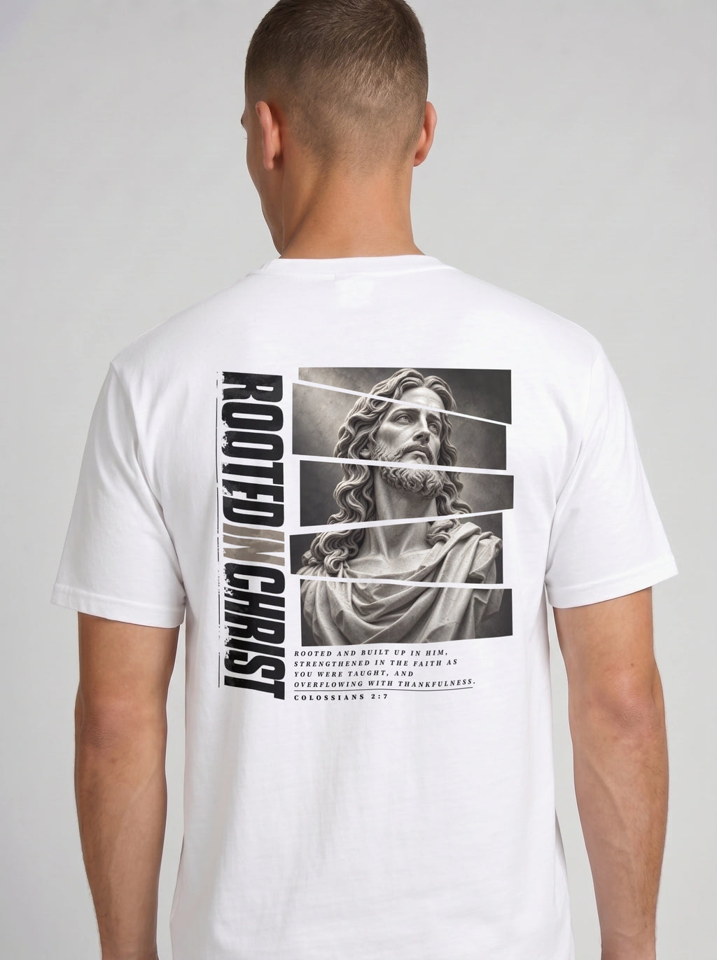 Person shown from behind wearing a white T-shirt with a grayscale Jesus graphic, vertical “Rooted in Christ” text, and Colossians 2:7.