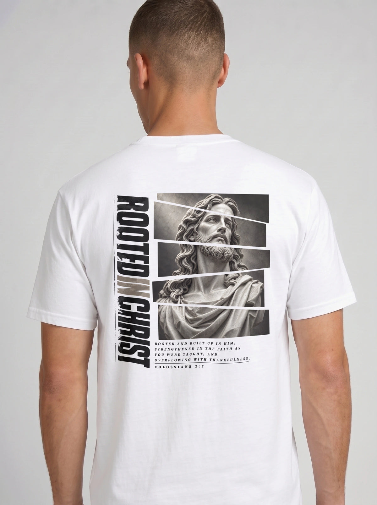 Person shown from behind wearing a white T-shirt with a grayscale Jesus graphic, vertical “Rooted in Christ” text, and Colossians 2:7.