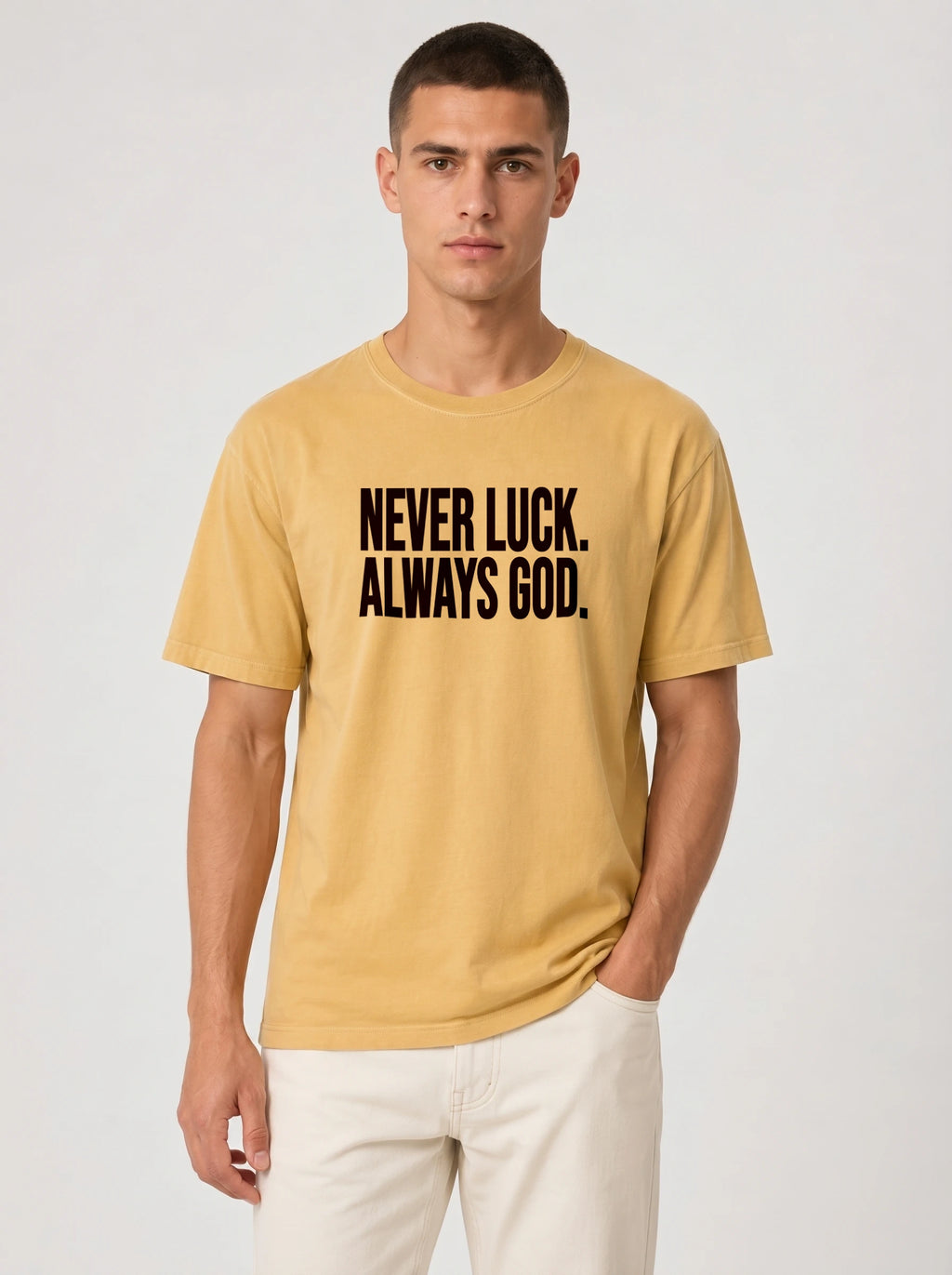 Person wearing a muted yellow T-shirt with black text reading “Never luck. Always God.”