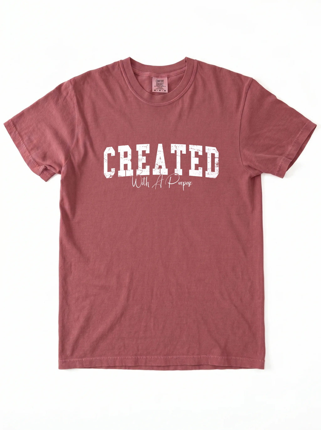 A dusty rose short-sleeve t-shirt with 'CREATED With A Purpose' printed in white on the front, laid flat against a white background.