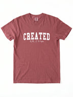 A dusty rose short-sleeve t-shirt with 'CREATED With A Purpose' printed in white on the front, laid flat against a white background.