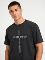 Person wearing a black T-shirt with a white cross design reading “John 3:16” and “For God so loved the world that he gave his one and only son.”