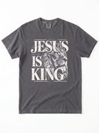 A dark gray crewneck t-shirt featuring a distressed white graphic print that reads 'JESUS IS KING' with a lion illustration, laid flat against a white background.