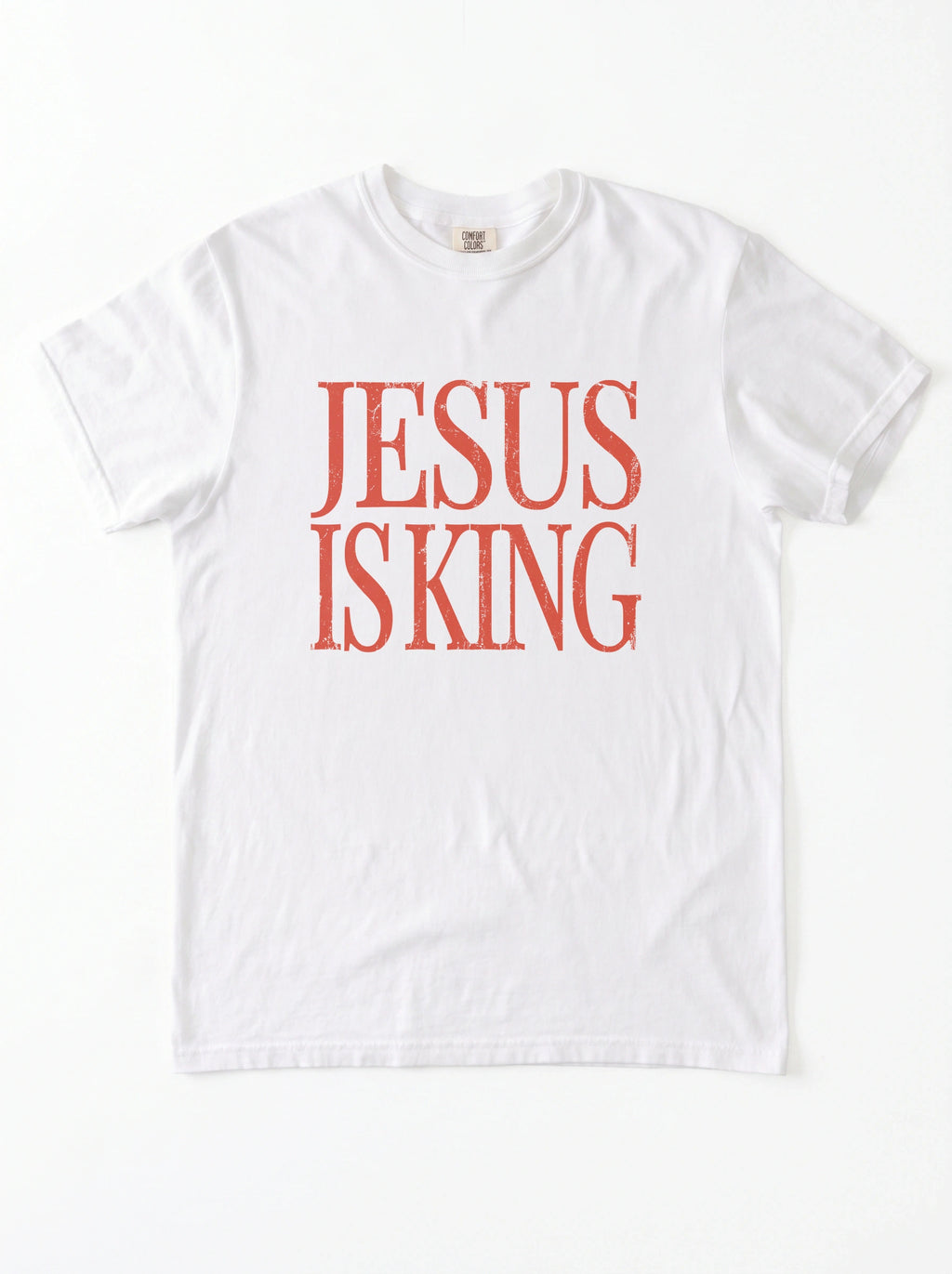 White T-shirt laid flat with distressed orange text reading “Jesus Is King.”