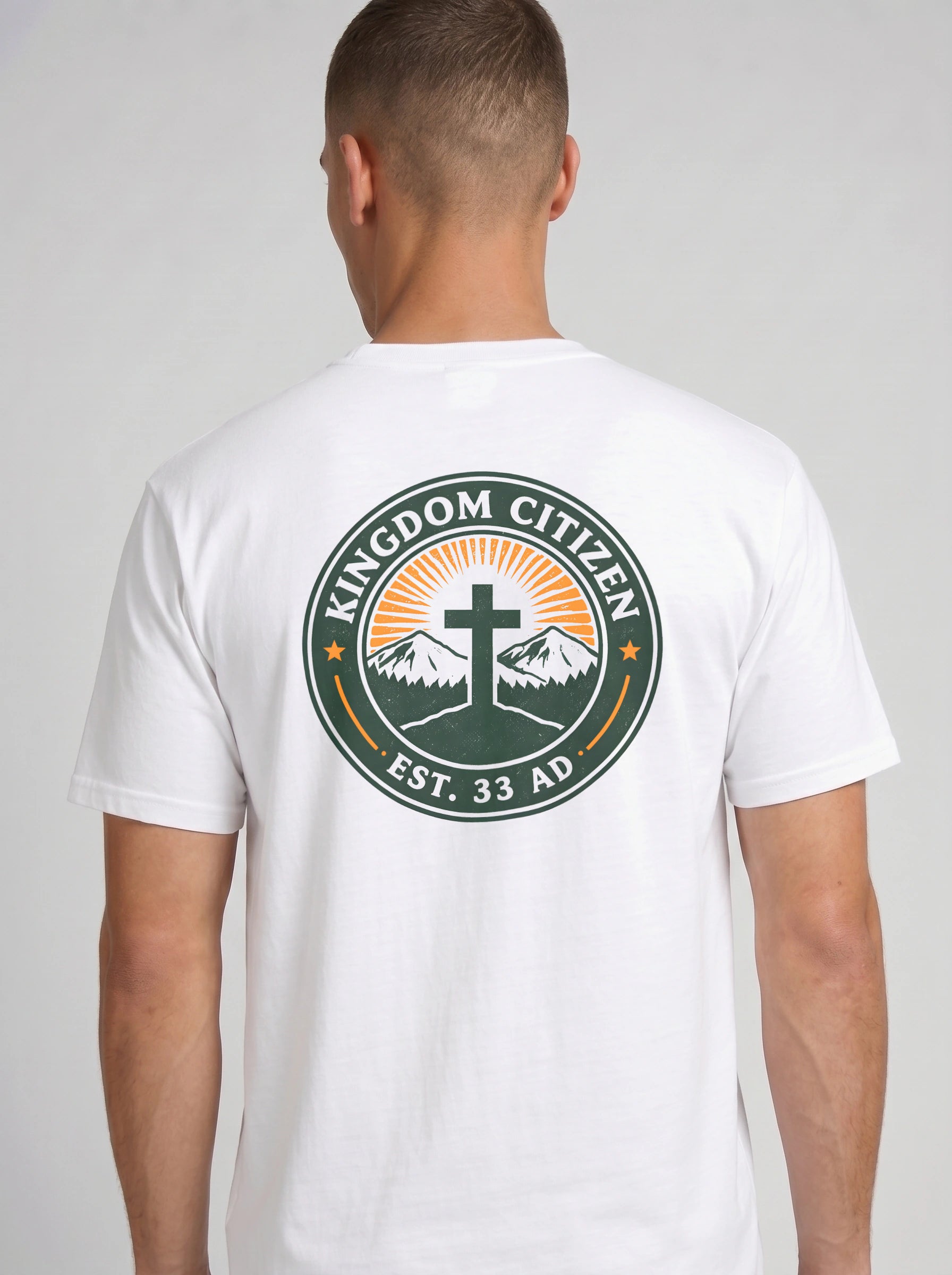 A man viewed from the back wearing a white t-shirt with a large circular graphic on the back. The graphic features a green border with the text 'KINGDOM CITIZEN' and 'EST. 33 AD.