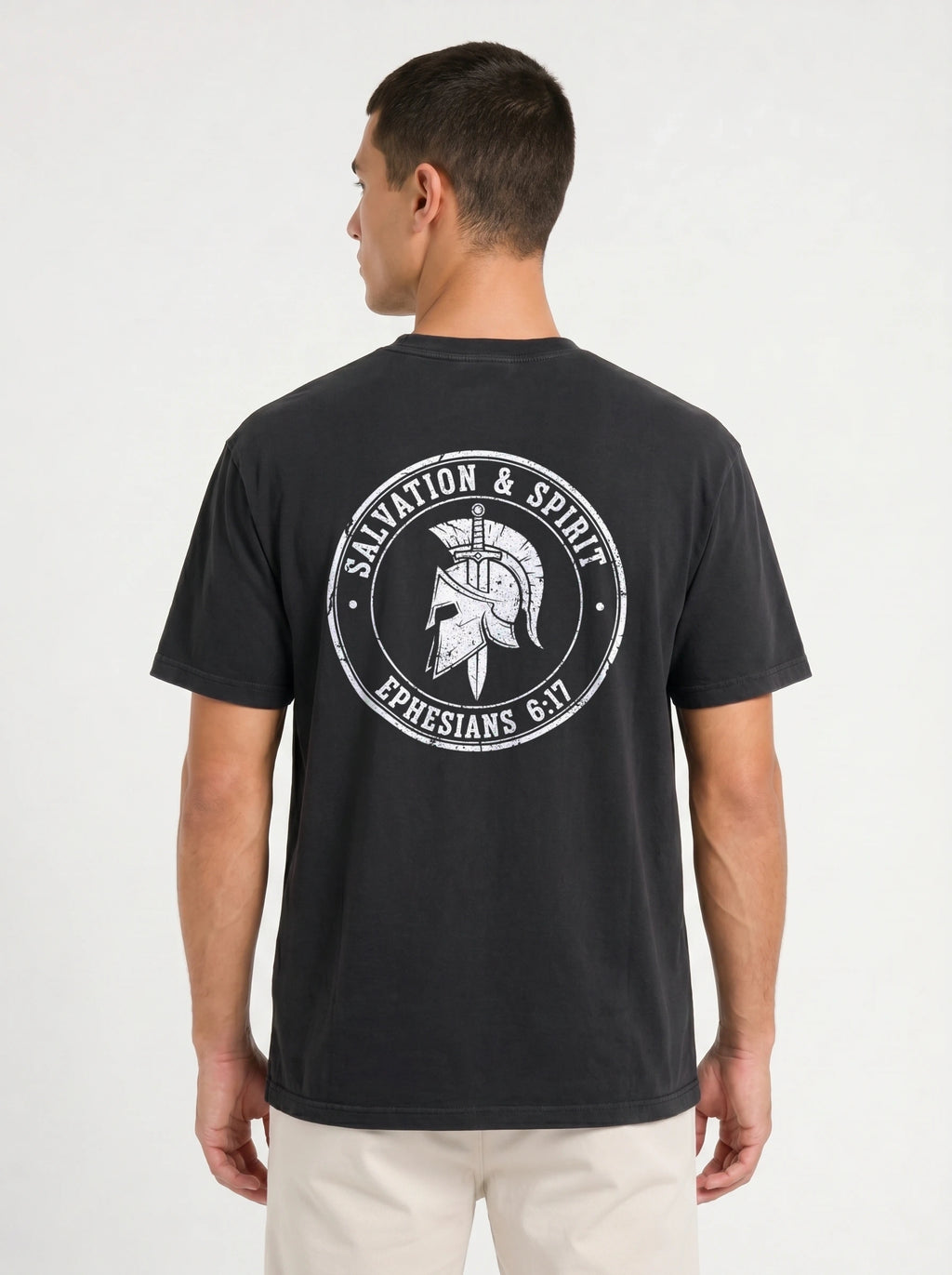 A man viewed from the back wearing a faded black t-shirt with a large white circular graphic on the back featuring a Spartan helmet and the text 'SALVATION & SPIRIT' and 'EPHESIANS 6:17'.