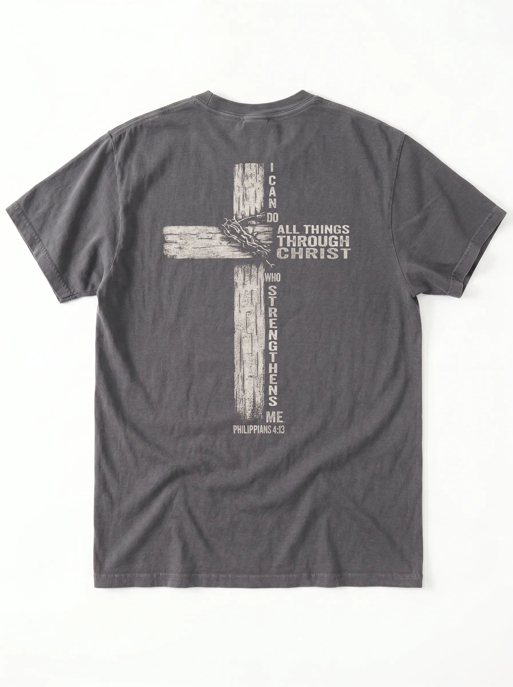 A dark gray crewneck t-shirt shown from the back, featuring a distressed biege graphic of a cross with the text 'I CAN DO ALL THINGS THROUGH CHRIST WHO STRENGTHENS ME' from Philippians 4:13.