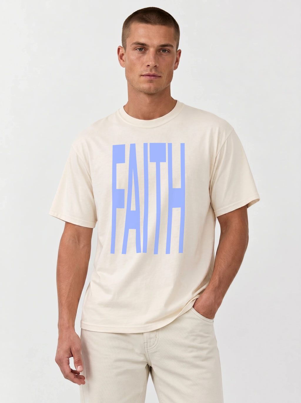 Person wearing a cream T-shirt with large light blue text reading “FAITH.”