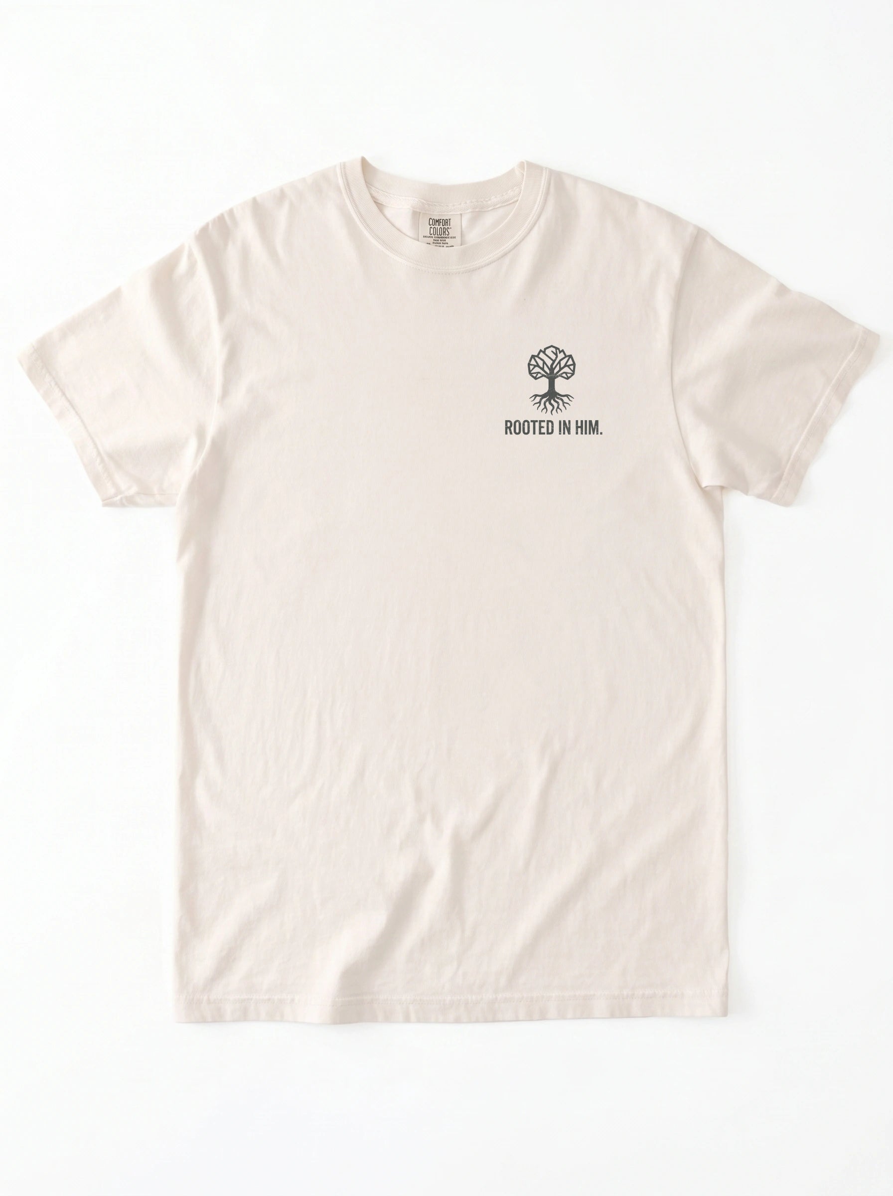 A light cream-colored short-sleeve t-shirt with a small black graphic of a tree and the text 'ROOTED IN HIM.' printed on the left chest, displayed flat against a white background.