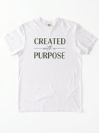 A white short-sleeve crewneck t-shirt with the text 'CREATED with a PURPOSE' printed in dark olive green on the chest, laid flat against a white background.