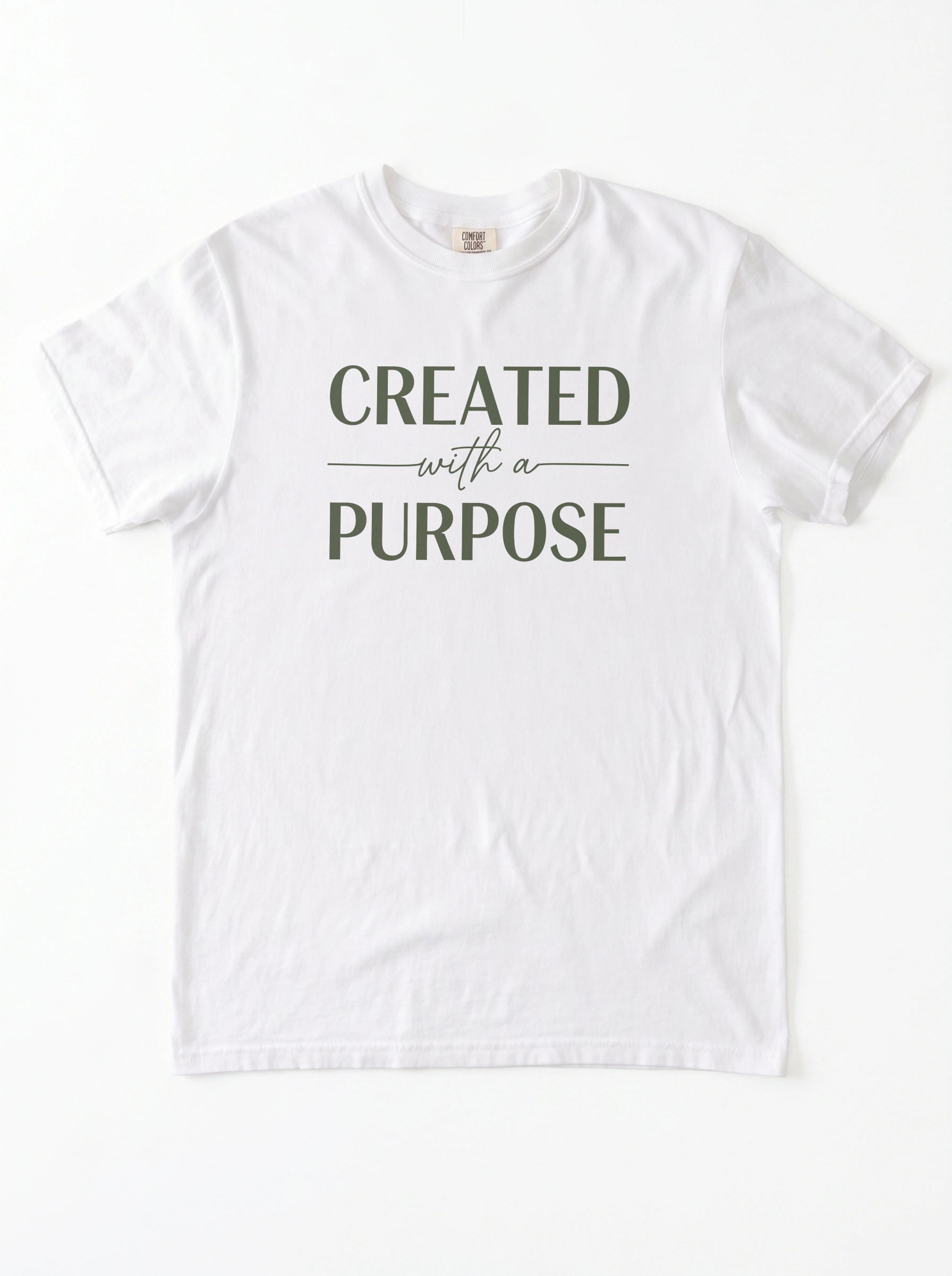 A white short-sleeve crewneck t-shirt with the text 'CREATED with a PURPOSE' printed in dark olive green on the chest, laid flat against a white background.