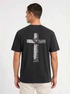 A man wearing a faded black t-shirt from the back, featuring a distressed biege graphic of a cross with the text 'I CAN DO ALL THINGS THROUGH CHRIST WHO STRENGTHENS ME' from Philippians 4:13.