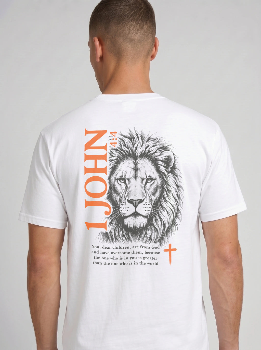 Person wearing a white T-shirt with a lion illustration, orange “1 John 4:4” and cross, and the verse “You, dear children, are from God and have overcome them, because the one who is in you is greater than the one who is in the world.”