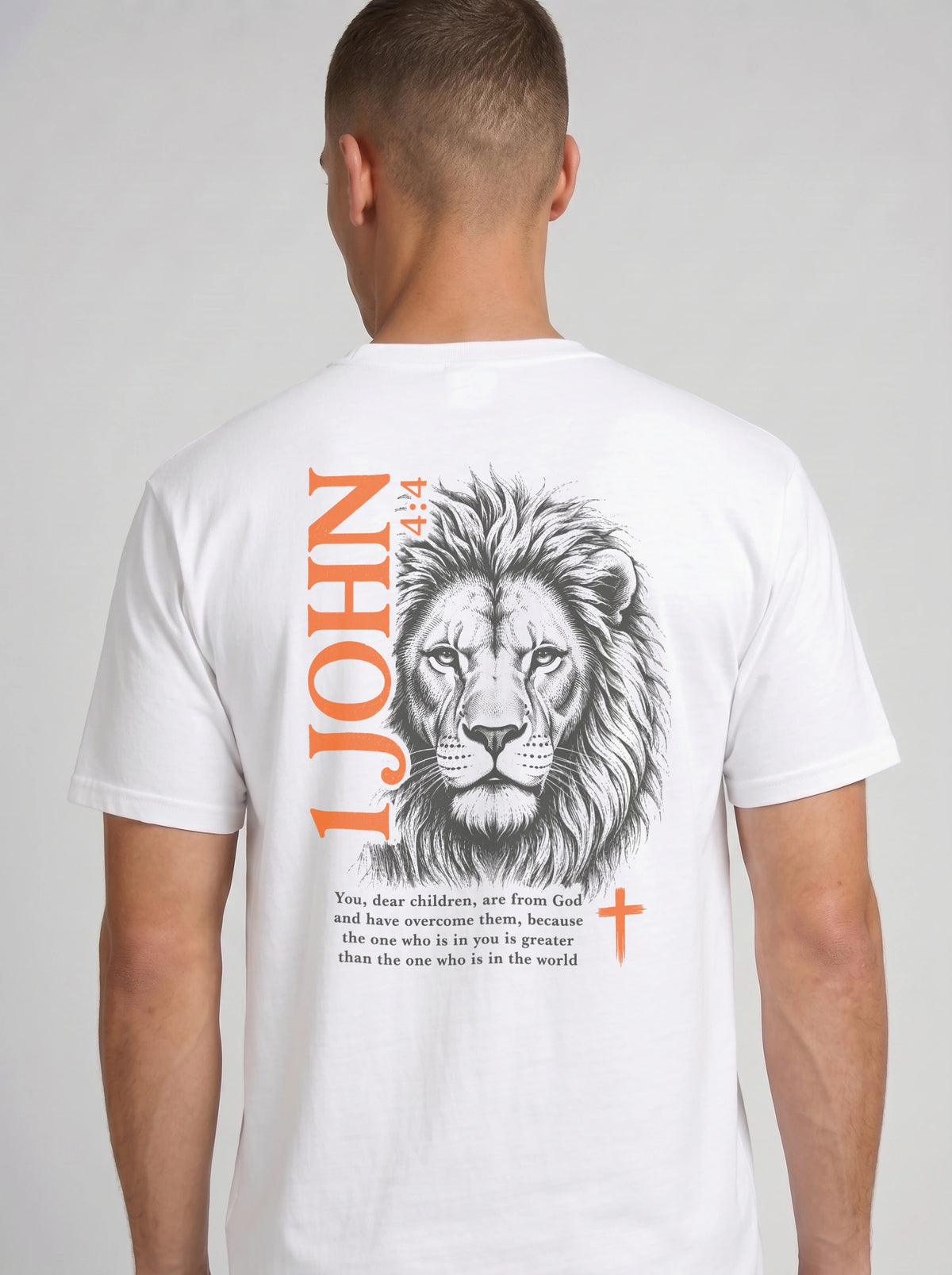 Person wearing a white T-shirt with a lion illustration, orange “1 John 4:4” and cross, and the verse “You, dear children, are from God and have overcome them, because the one who is in you is greater than the one who is in the world.”