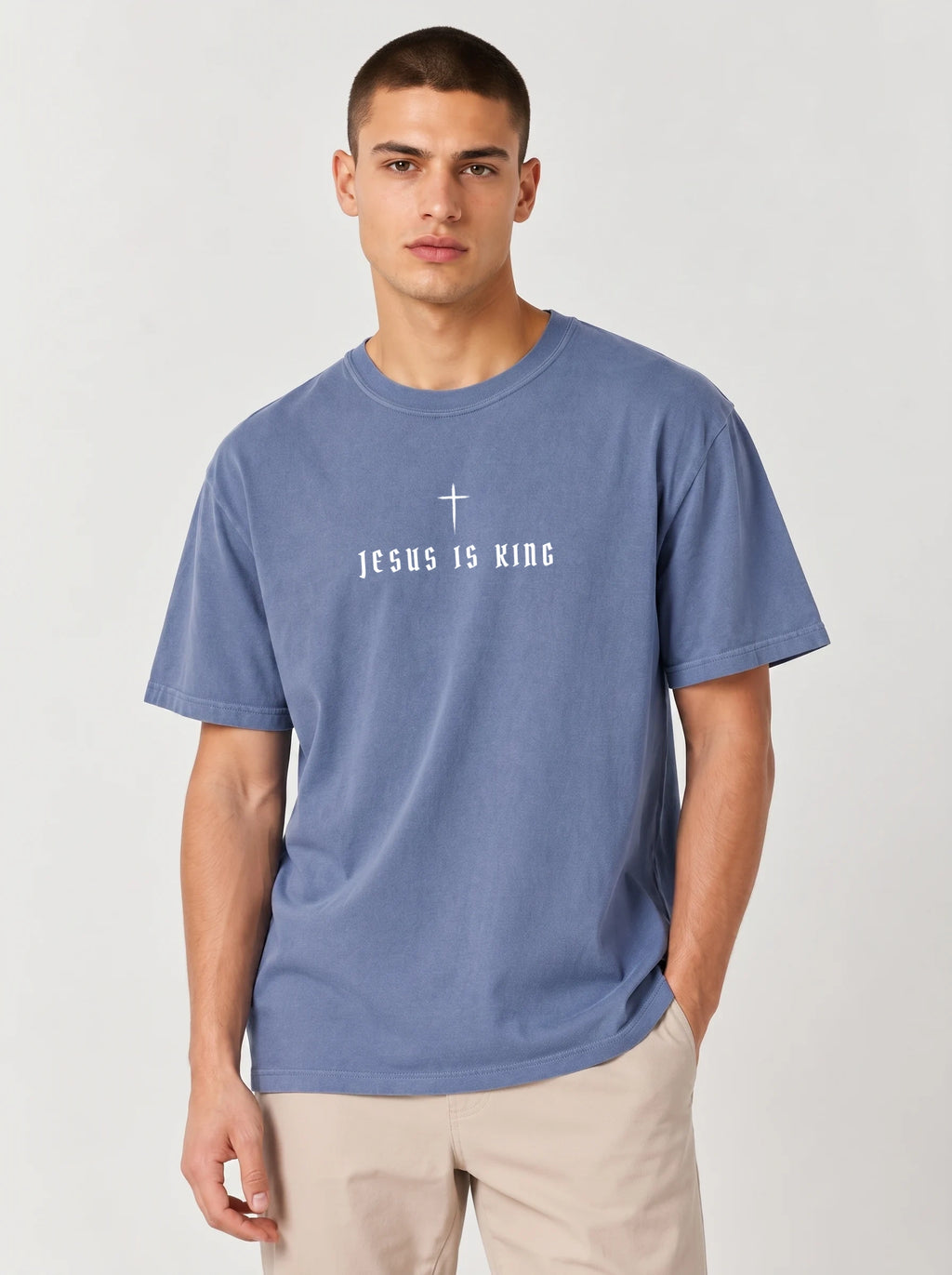 Person wearing a faded blue T-shirt with a white cross above the text “Jesus Is King.”