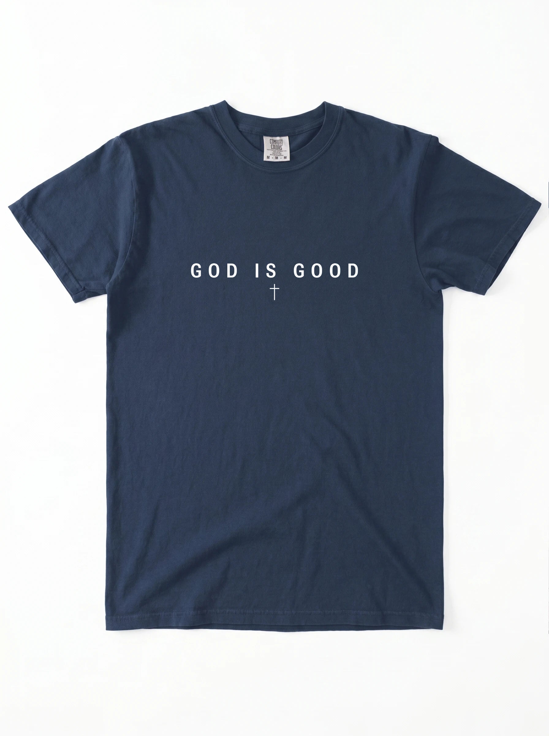 A navy blue short-sleeve t-shirt with the phrase 'GOD IS GOOD' printed in white across the chest, with a small white cross symbol underneath, laid flat against a white background.