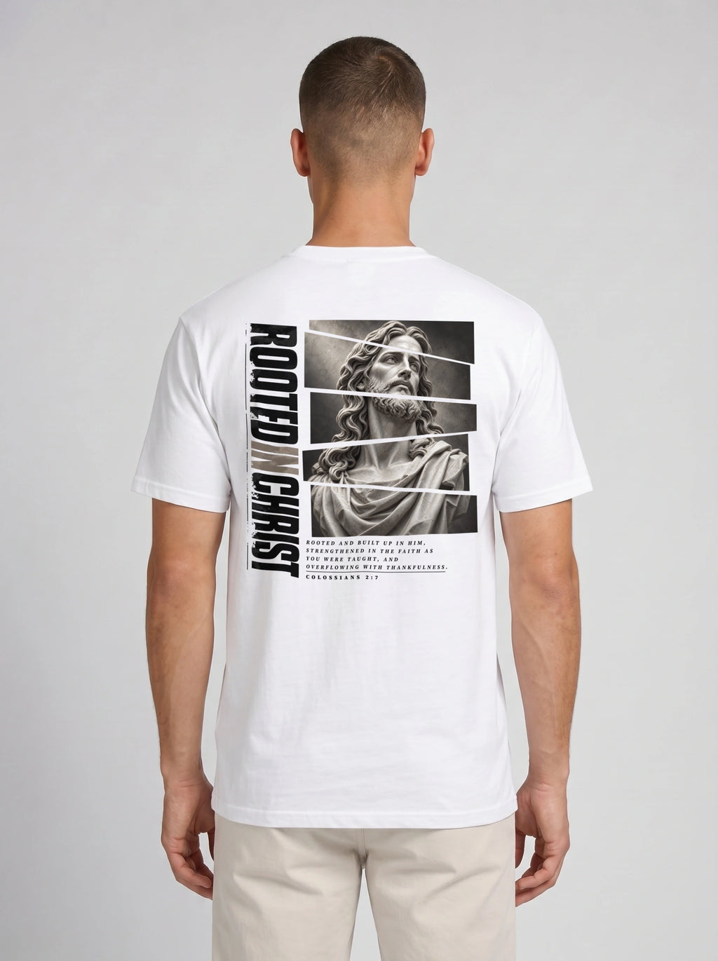 Person shown from behind wearing a white T-shirt with a grayscale Jesus graphic, vertical “Rooted in Christ” text, and Colossians 2:7.