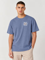 Person wearing a faded blue T-shirt with a small chest design reading “TRUST GOD’S PLAN.”