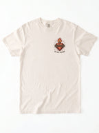 Cream T-shirt laid flat with a flaming sacred heart wrapped in thorns and the text “By His Wounds.”