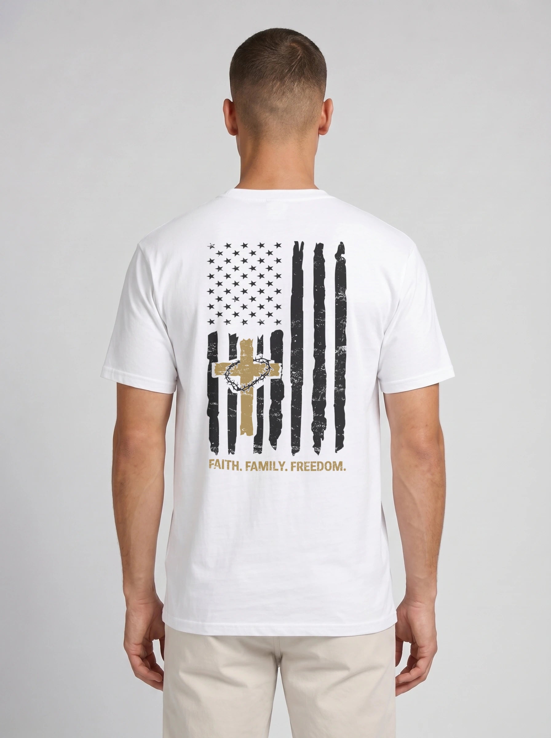 A man viewed from the back wearing a white short-sleeve t-shirt with a distressed black and gold American flag graphic and the words 'FAITH, FAMILY, FREEDOM.' printed below it.