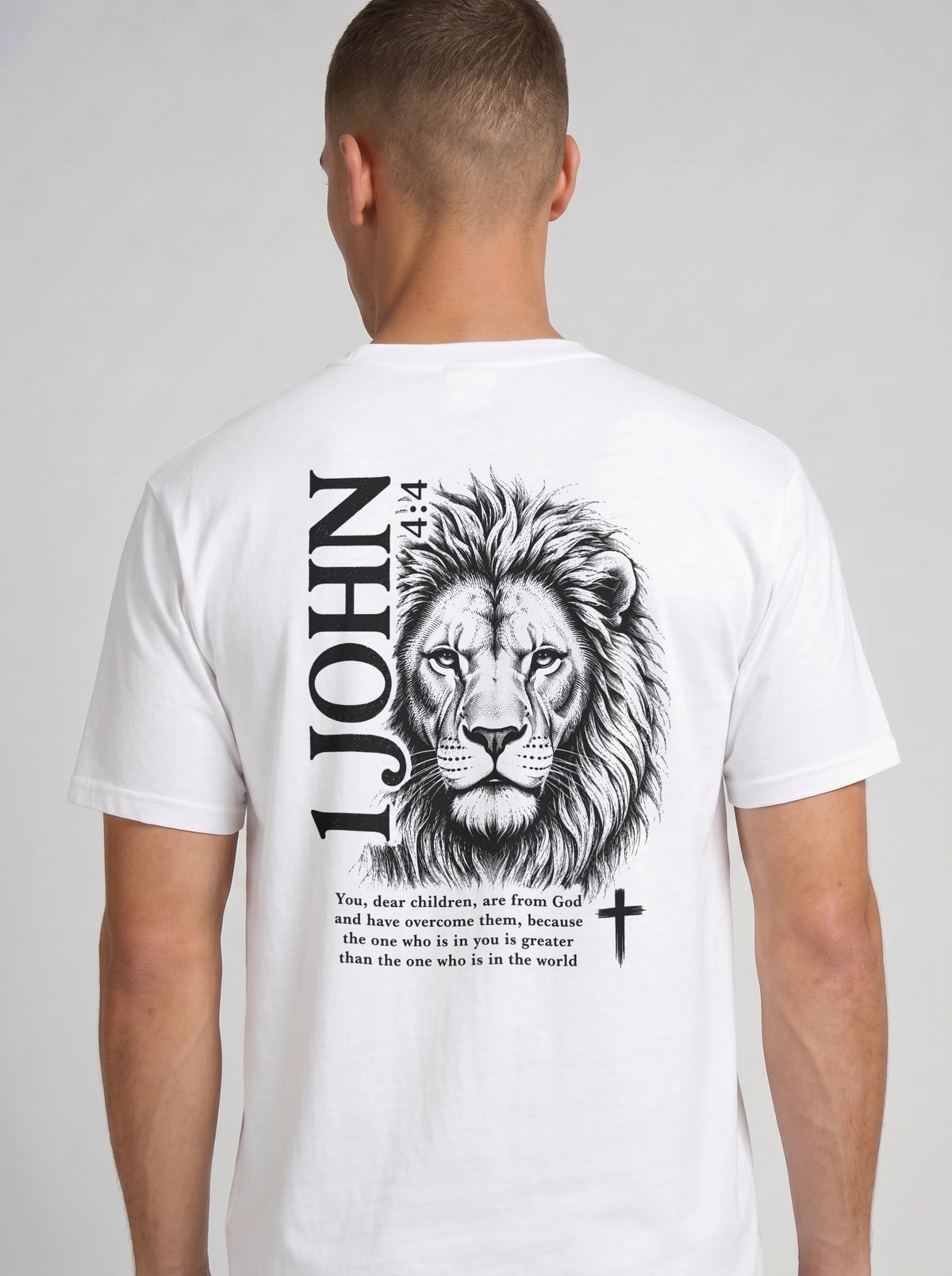 Person wearing a white T-shirt with a black lion illustration, cross, “1 John 4:4,” and the verse text, “You, dear children, are from God and have overcome them, because the one who is in you is greater than the one who is in the world.”