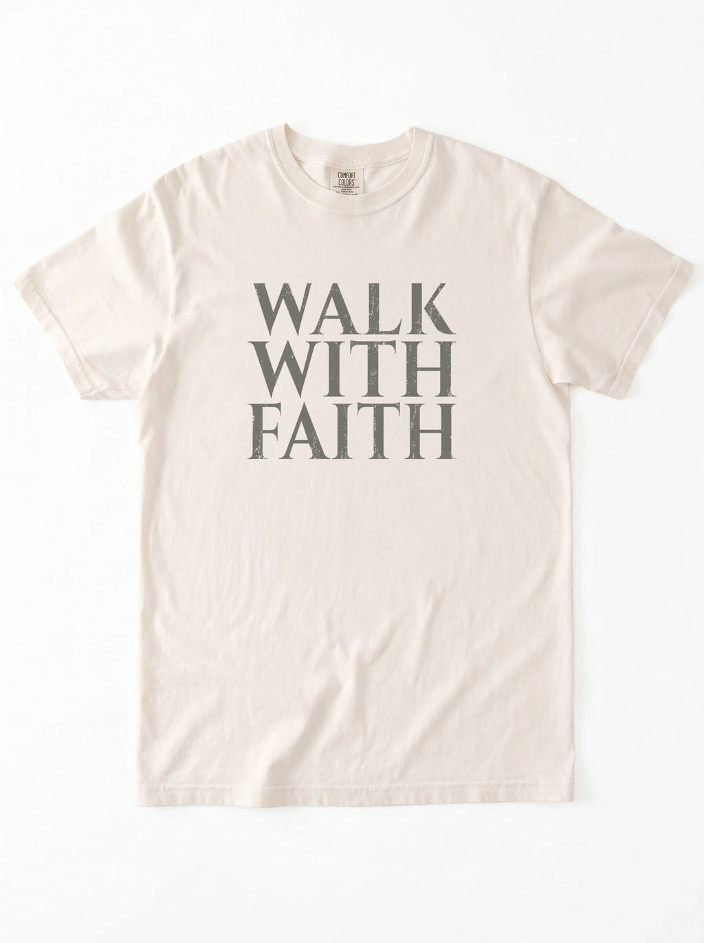 Cream T-shirt laid flat with distressed gray text reading “Walk With Faith.”