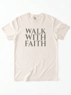 Cream T-shirt laid flat with distressed gray text reading “Walk With Faith.”