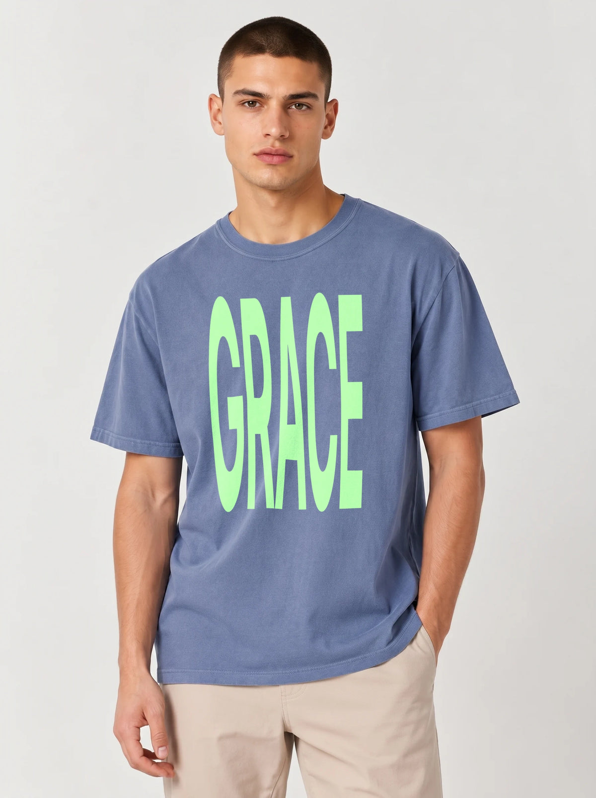Person wearing a faded blue T-shirt with large neon green text reading “GRACE.”