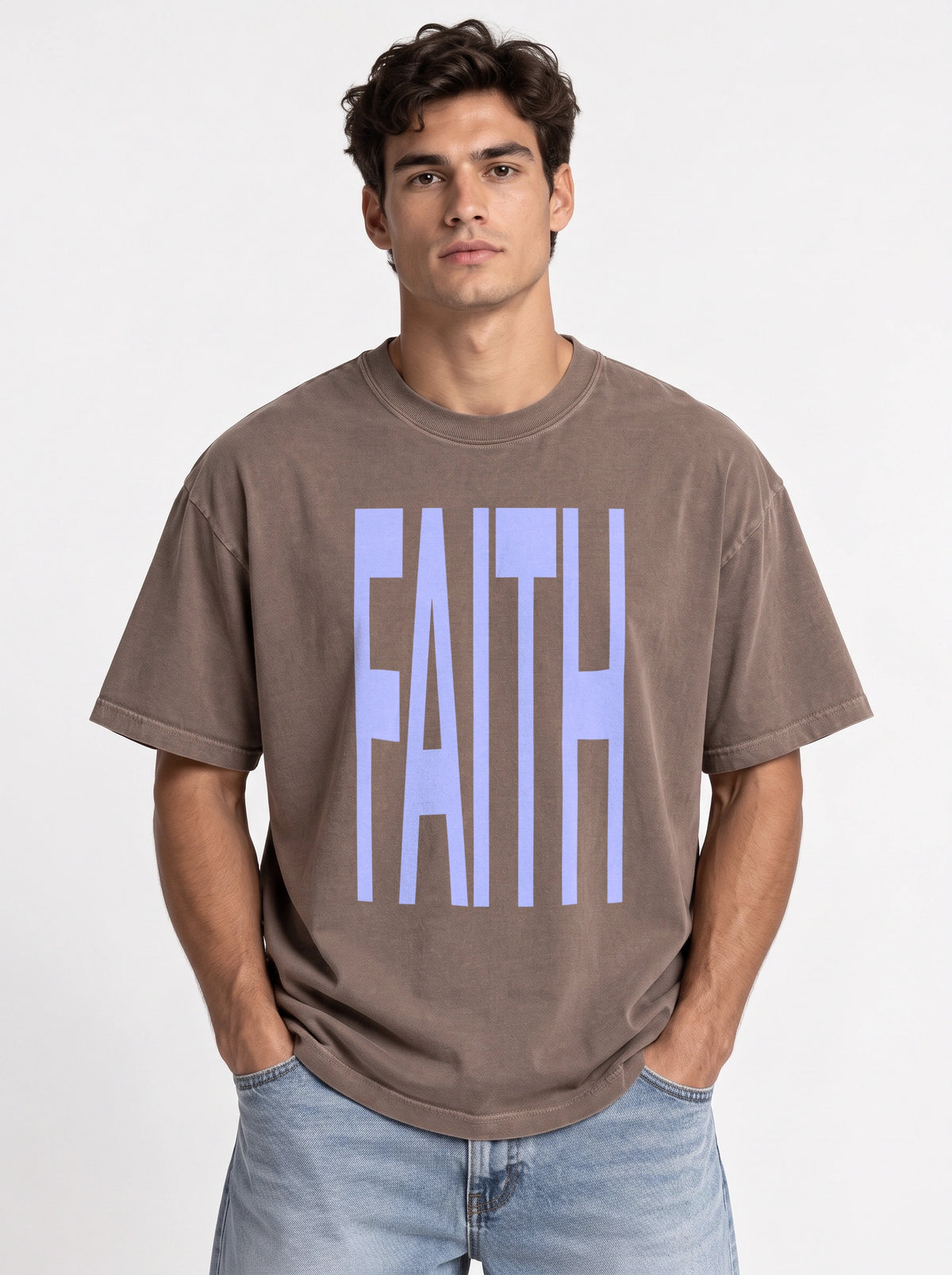 Person wearing a faded brown T-shirt with large light blue text reading “FAITH.”