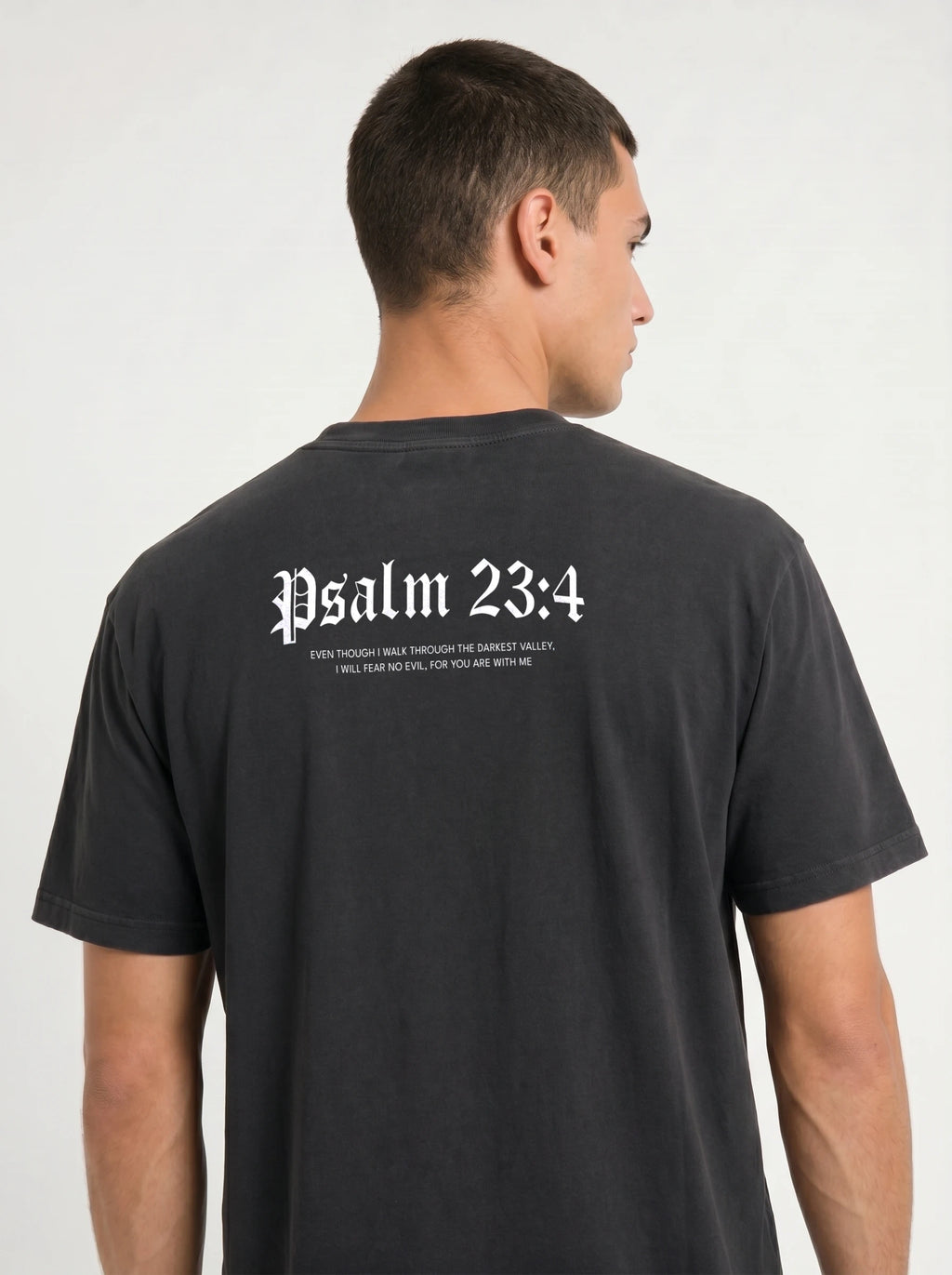 A man shown from the back wearing a black t-shirt with 'Psalm 23:4' printed in white Gothic lettering across the upper back.