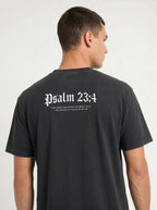 A man shown from the back wearing a black t-shirt with 'Psalm 23:4' printed in white Gothic lettering across the upper back.