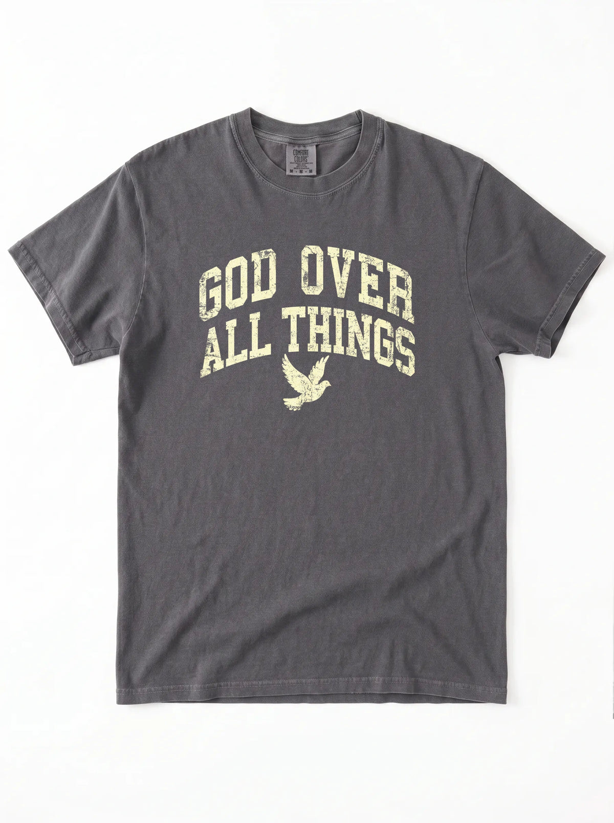 Flat lay view of a charcoal short-sleeve t-shirt on a white background, featuring the distressed yellow text "GOD OVER ALL THINGS" and a dove graphic on the chest.