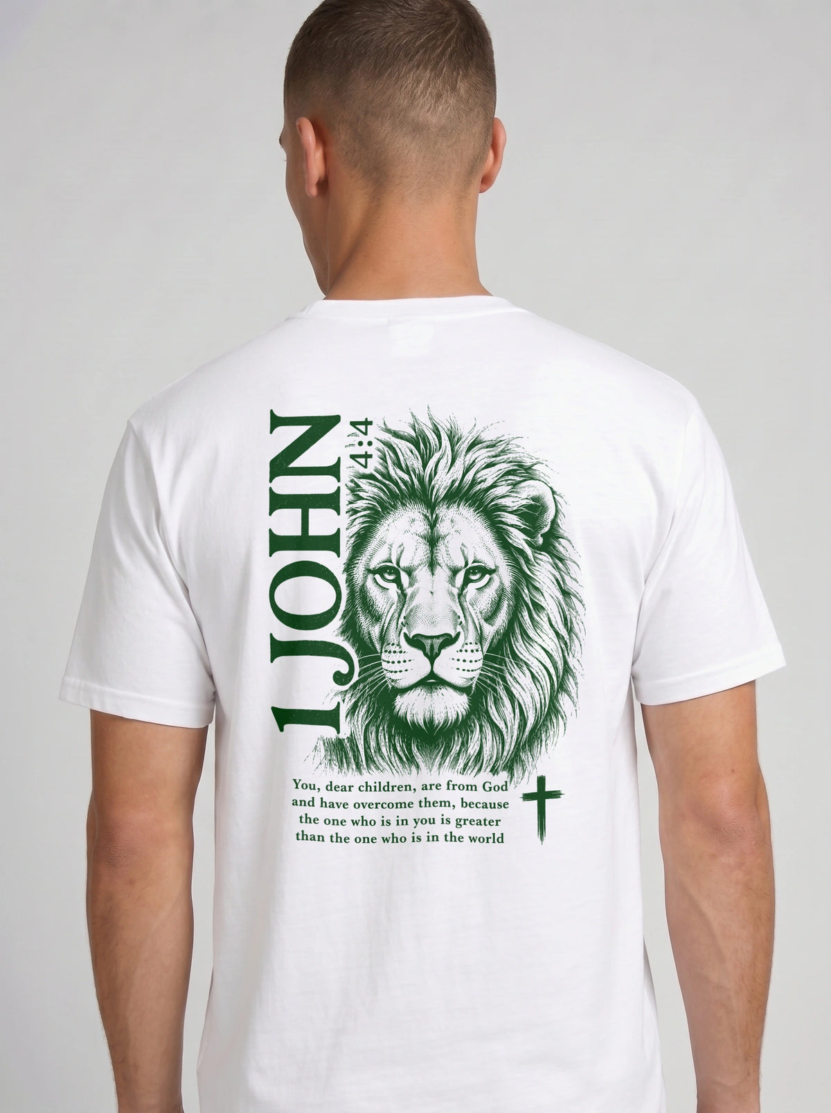 Person wearing a white T-shirt with a green lion illustration, cross, “1 John 4:4,” and the verse text, “You, dear children, are from God and have overcome them, because the one who is in you is greater than the one who is in the world.”