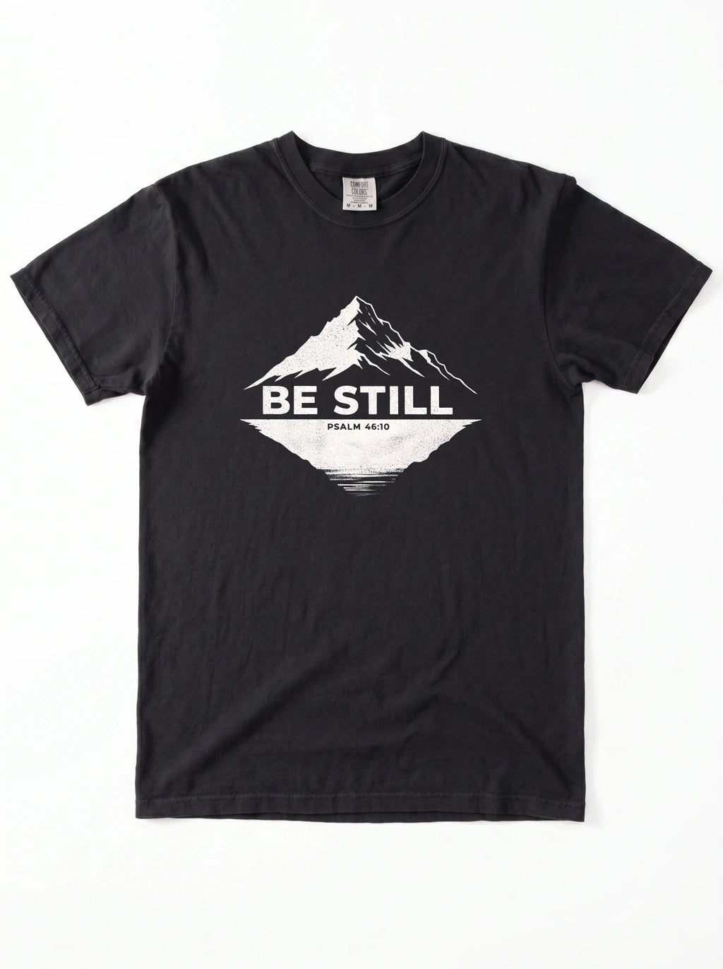 A black short-sleeve crewneck t-shirt with a white graphic on the chest showing a mountain peak, a lake reflection, and the text 'BE STILL' and 'PSALM 46:10'.