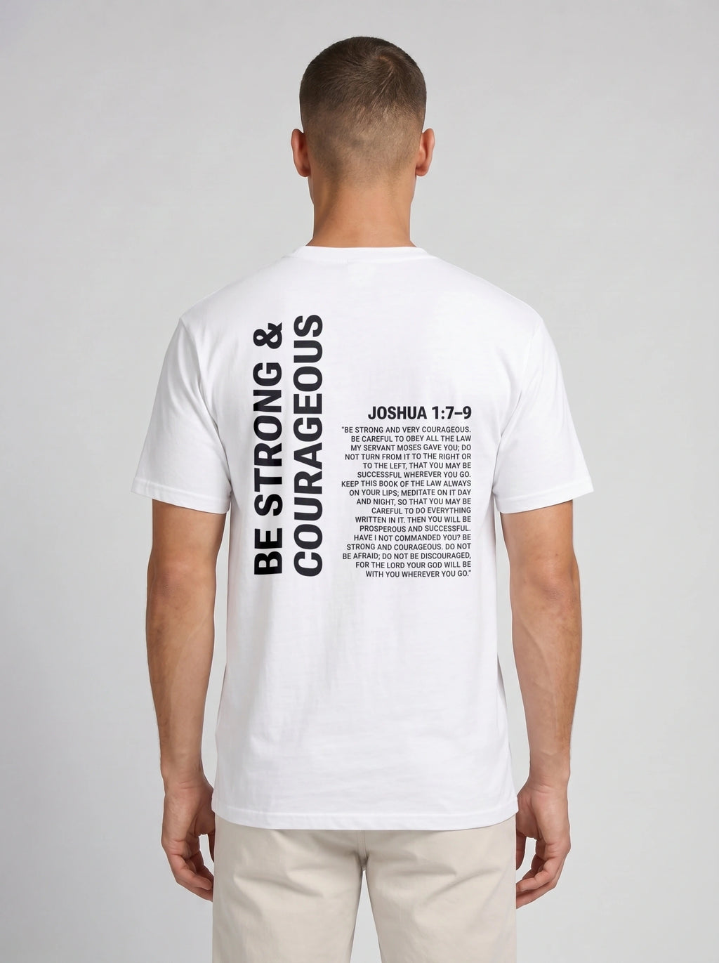 Person wearing a white T-shirt with a large back print reading “Be strong & courageous” beside Joshua 1:7–9.