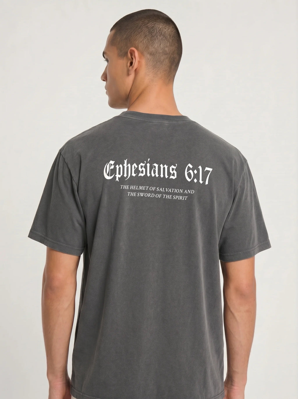 A man viewed from the back wearing a dark gray t-shirt with 'Ephesians 6:17' printed in white gothic font across the upper back.
