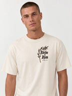 Cream T-shirt with a leafy chest graphic reading “Abide in Him” and “John 15:4.”