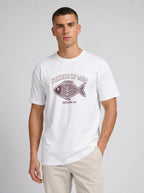 A man wearing a white crewneck t-shirt with a graphic print of a fish and the text 'FISHERS OF MEN' and 'MATTHEW 4:19' in a dark maroon color, paired with beige pants, against a light gray studio background.