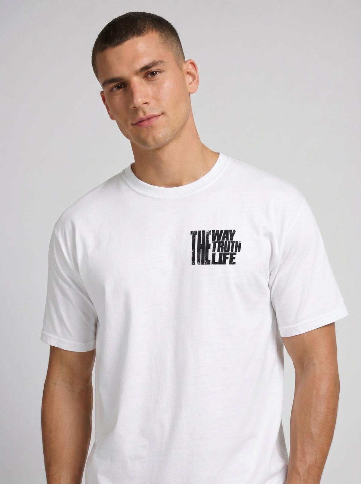 Person wearing a white T-shirt with a small distressed chest print reading “The Way The Truth The Life.”