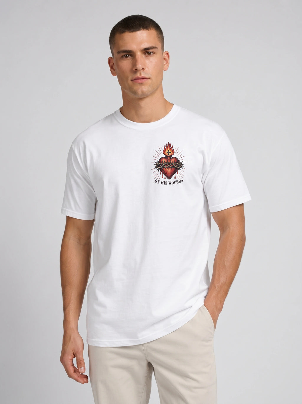 White T-shirt with a flaming sacred heart wrapped in a crown of thorns and the text “By His Wounds.”