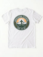 A white short-sleeve t-shirt laid flat against a white background, featuring a circular graphic on the chest with the text 'KINGDOM CITIZEN' and 'EST. 33 AD' surrounding a cross, mountains, and sunburst.